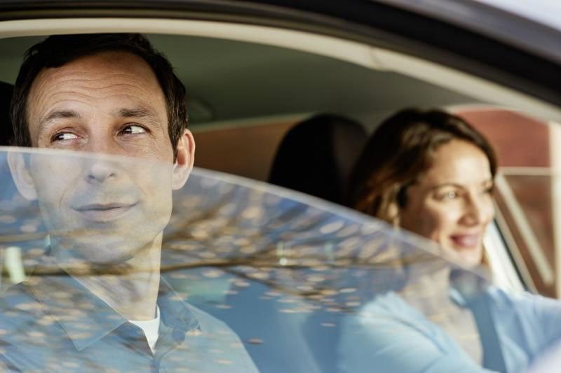 a woman is holding a surfboard next to a car on the beach .