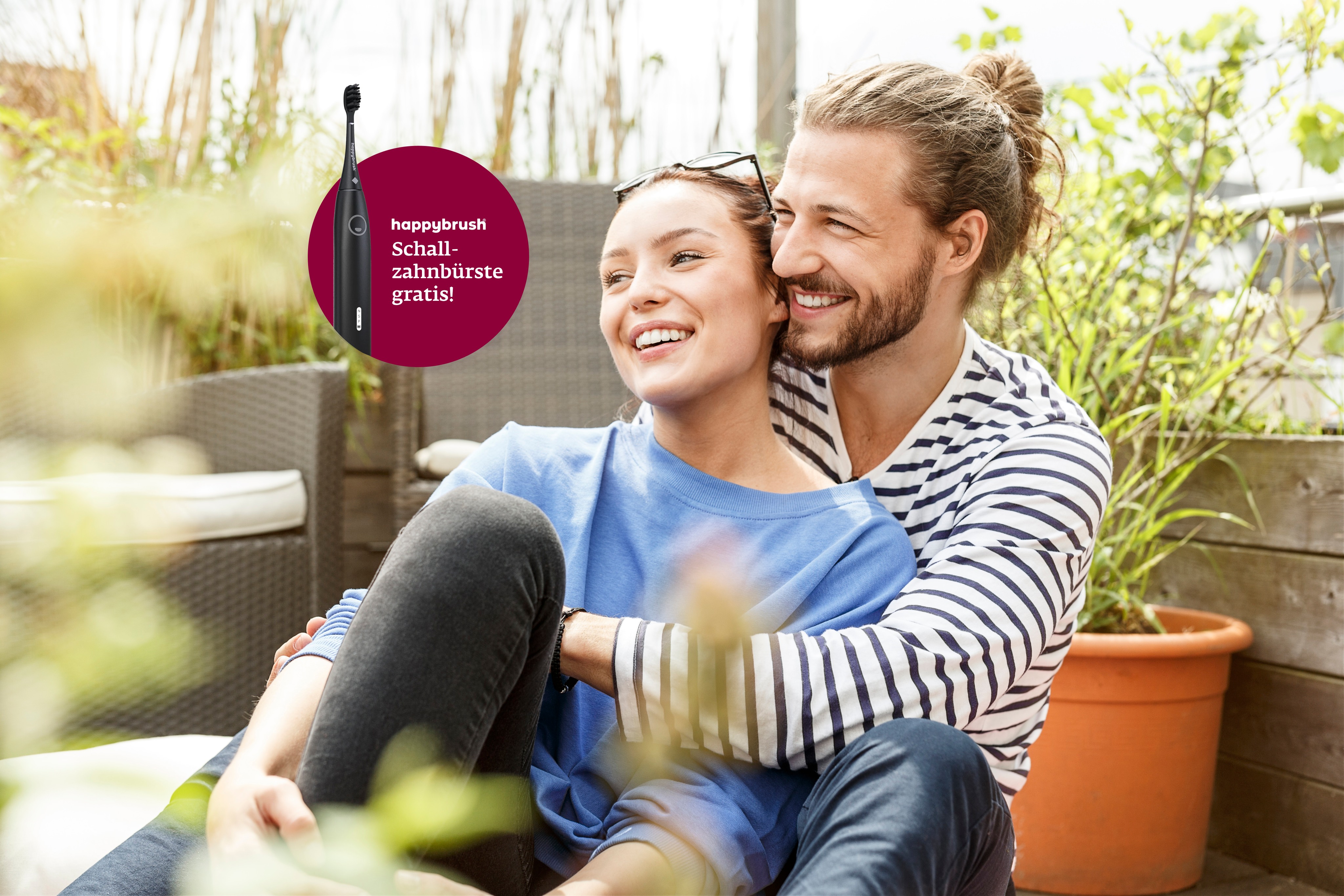 A happy couple embracing on a balcony, with a "happybrush sonic toothbrush free!" offer overlay.