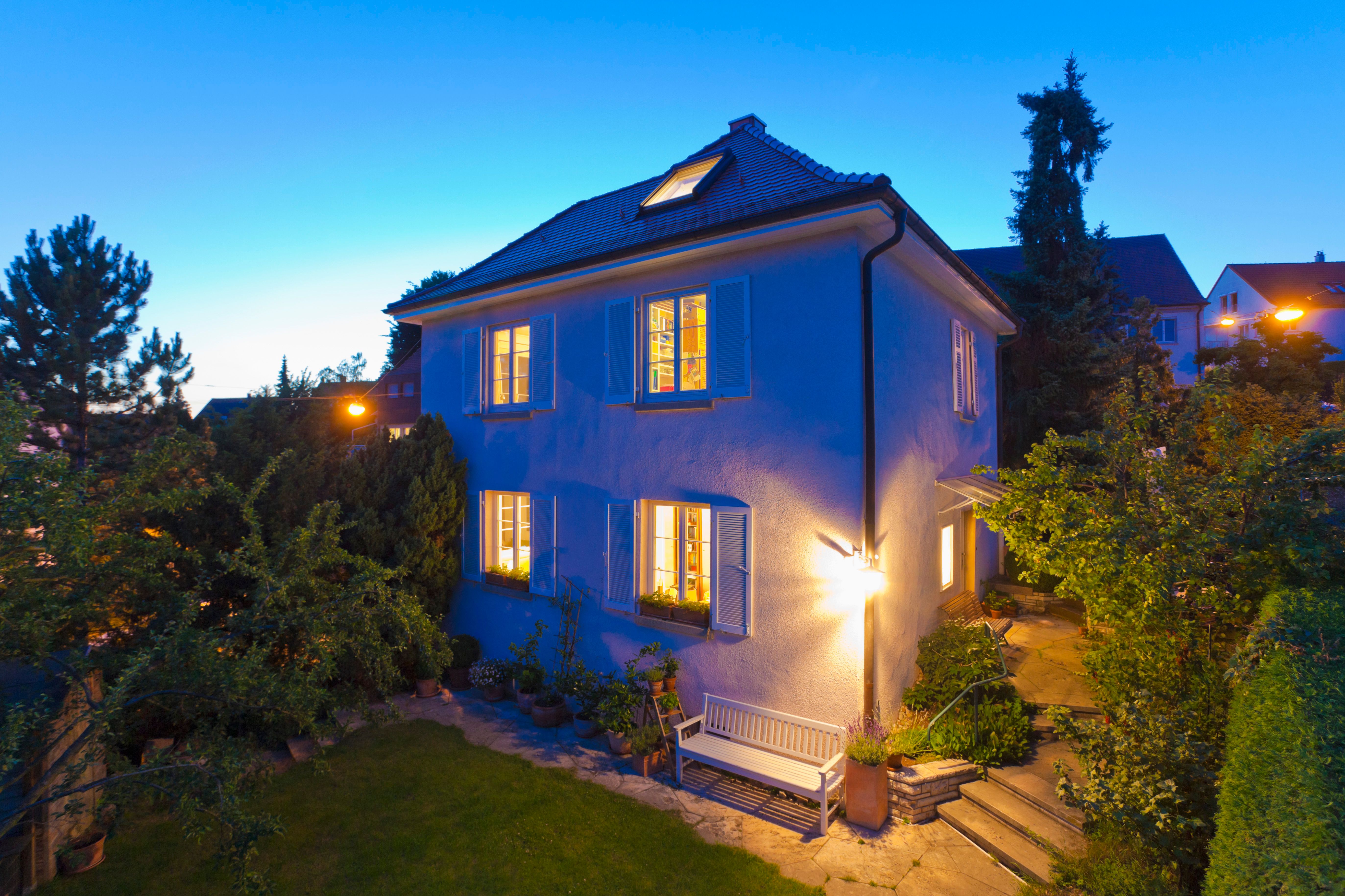 a large house with a bench in front of it is lit up at night .