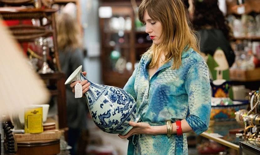 a woman is holding a blue and white vase in an antique store .