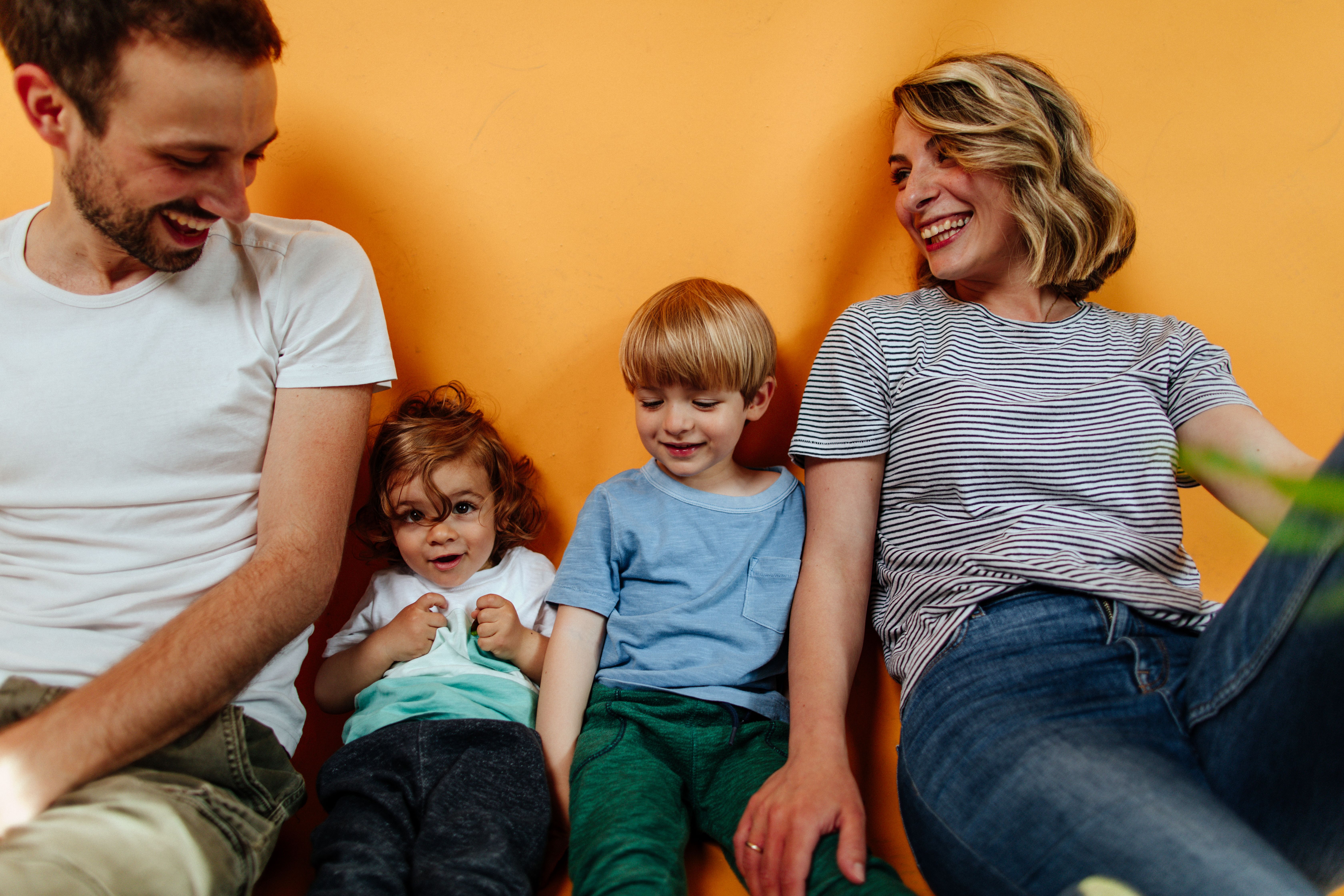a family is sitting next to each other on a yellow background .