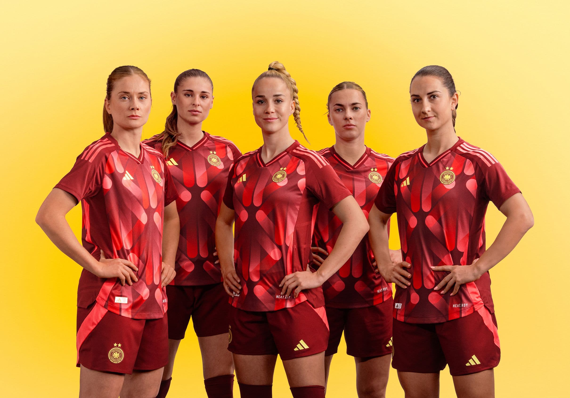 eine Gruppe von Frauen, die nebeneinander stehen und rote Fußballtrikots tragen.