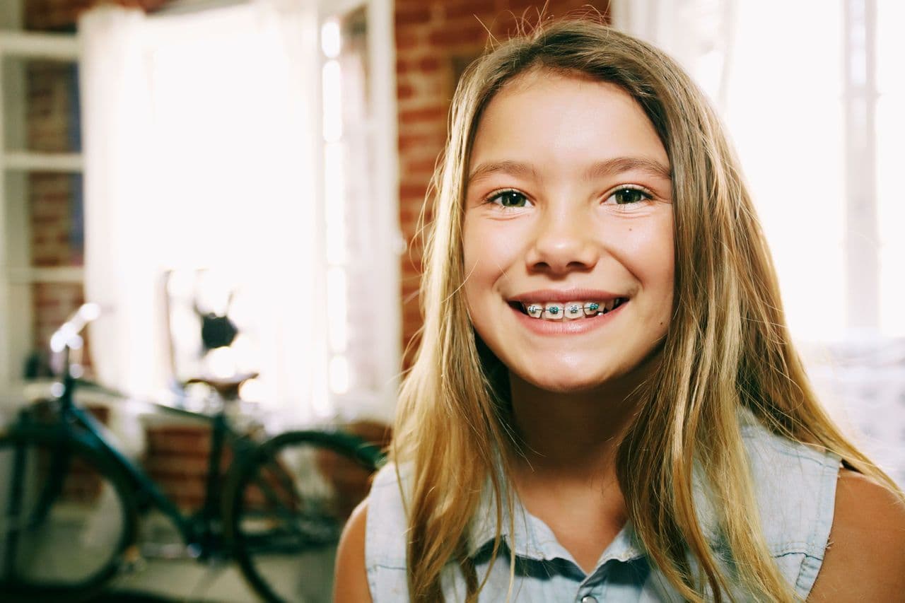 a young girl with braces on her teeth is smiling for the camera .