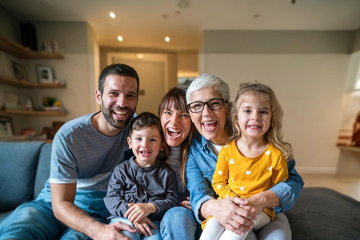 Eine Familie posiert für ein Foto, während sie auf einem Sofa sitzt.